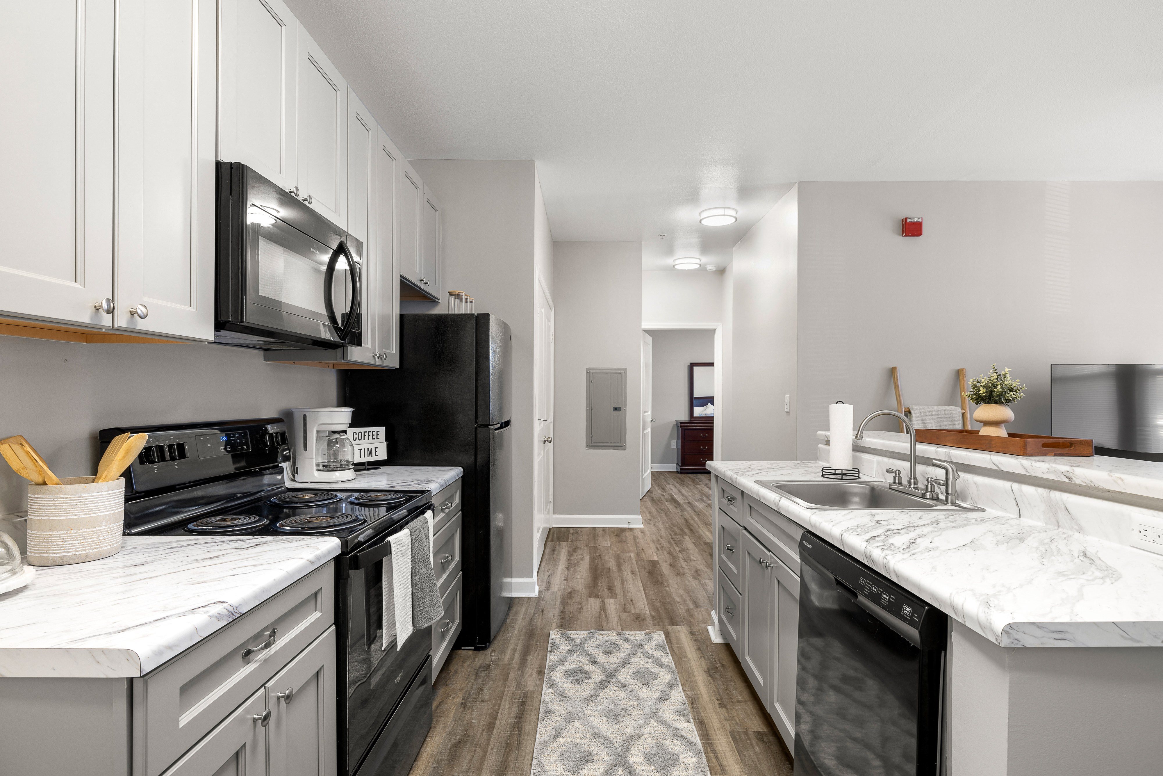 a kitchen with white cabinets and black appliances and white counter tops